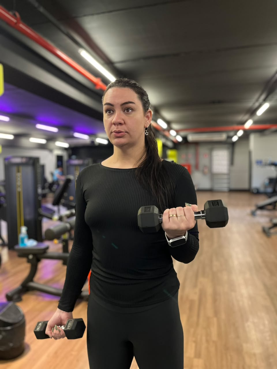 Aluna sorrindo durante intervalo do treino em academia iluminada